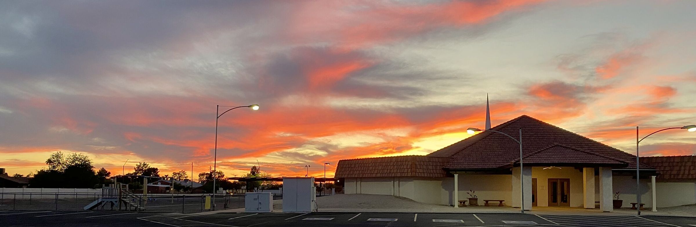Avondale Baptist Church at sunset: the steeple and red tile roof against an orange and pink Arizona sky