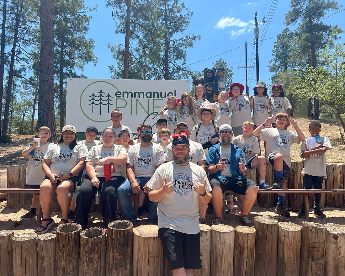 Kids in matching shirts at camp under the pines