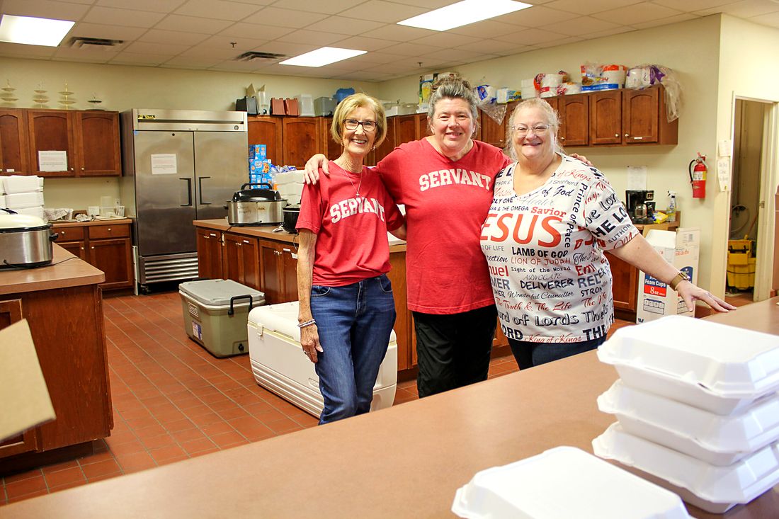 Three volunteers smiling in the church kitchen