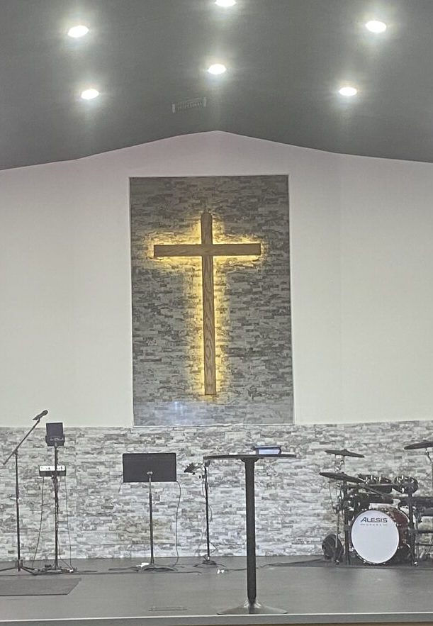 The lighted cross on the stone wall of the Worship Center